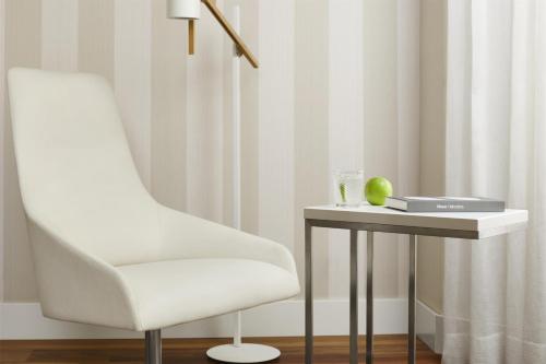 a white chair sitting next to a table with a side table at NH Collection Madrid Colón in Madrid