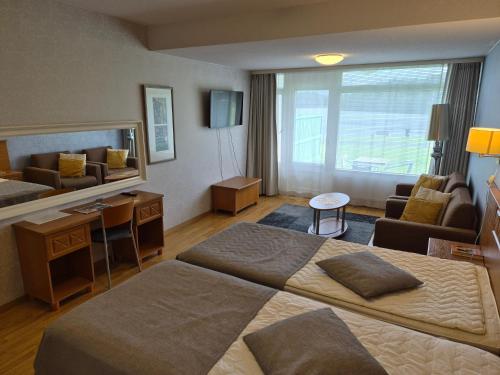 ein Hotelzimmer mit zwei Betten und einem Wohnzimmer in der Unterkunft Apartamentos Ikaalisten Kylpylä Terme JPLomat in Ikaalinen