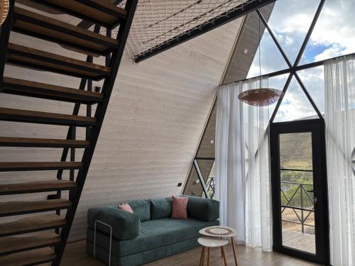 a living room with a green couch and a staircase at Space Trip Hotel in Artavaz