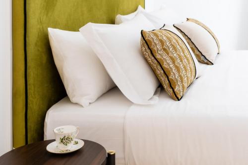 a bed with pillows and a table with a cup on it at Marmori Suites Cagliari in Cagliari