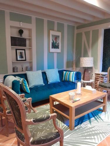 a living room with a blue couch and a table at Le Logis Fleurs et jardins de Pitry in Thierville