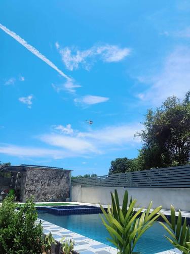 an airplane is flying over a swimming pool at อู่ตะเภาโฮมสเตย์byต้นไทร in Ban Nong Sa