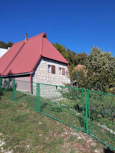 a building with a red roof behind a fence at Seoski dom in Šavnik