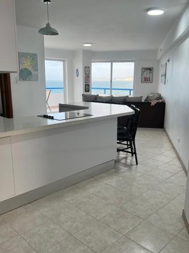 a kitchen with a white counter and a living room at Bello Apartamento en Playa Lido, lechería in El Morro de Barcelona