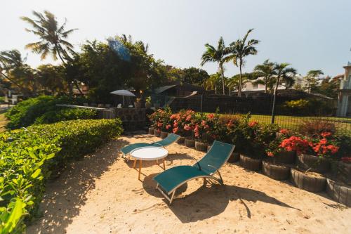 zwei Stühle und ein Tisch im Sand mit Blumen in der Unterkunft Beachfront duplex with direct beach access in Cap Malheureux