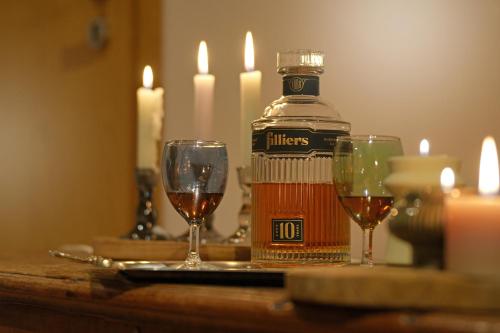 a bottle of alcohol and two wine glasses on a table at La Forge - Chambres d'hôtes en Ardenne in Wellin
