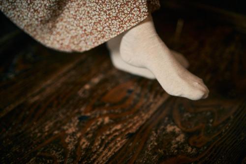 a woman wearing white socks standing on a wooden floor at Sokuan a 120 Year Old Art Filled Inn in Yui