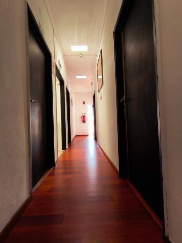 an empty hallway with black doors and a wooden floor at Lagoas in Tavira