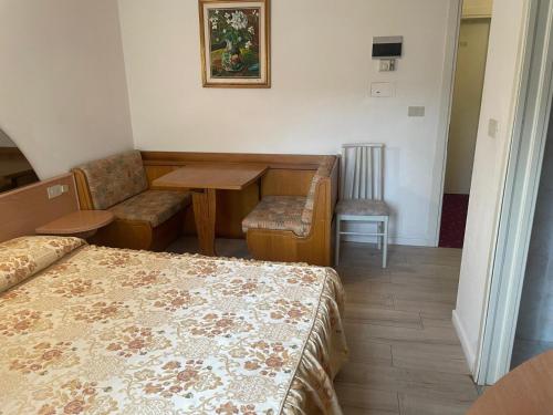 a hotel room with a bed and a table and chair at Hotel Villa Luisa in Lignano Sabbiadoro