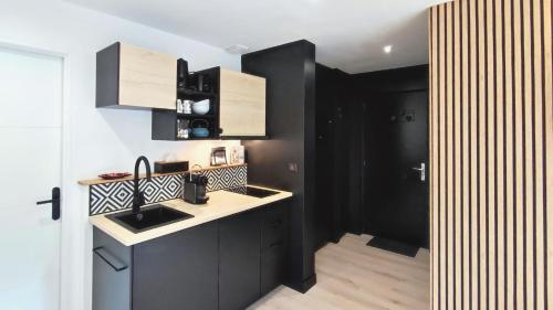 a kitchen with black and white cabinets and a sink at T3 tout neuf 6 personnes proche centre ville in Luchon