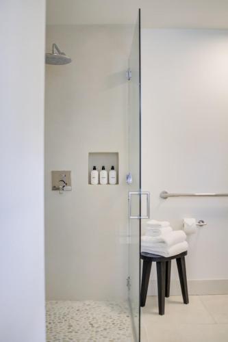 a bathroom with a glass shower with a stool at Casa Valerio - Boutique Suites in Downtown Santa Barbara in Santa Barbara