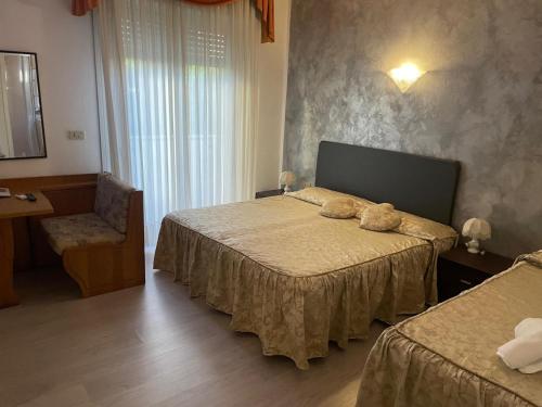 a hotel room with two beds and a chair at Hotel Villa Luisa in Lignano Sabbiadoro