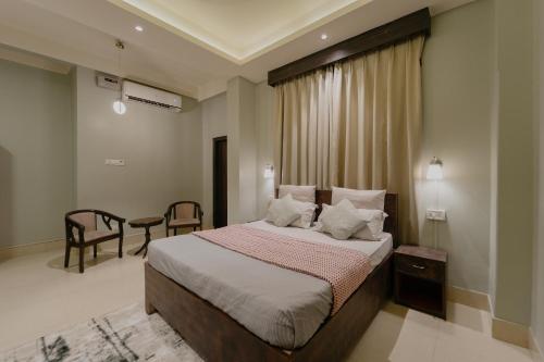 a bedroom with a bed and a table and chairs at Omnia By Alhanney in Guwahati