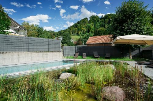 a swimming pool in a yard with an umbrella at Relaxed Urban Living - Aparthotel und Boardinghouse in Dornbirn