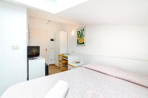 a white bedroom with a bed and a television at Hotel Villa Luisa in Lignano Sabbiadoro