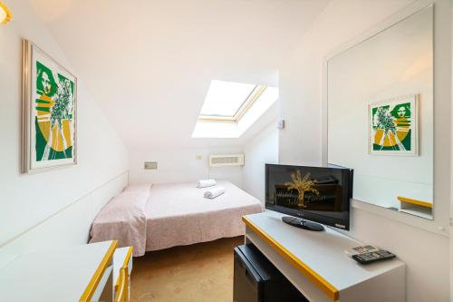 a bedroom with a bed and a desk with a computer at Hotel Villa Luisa in Lignano Sabbiadoro