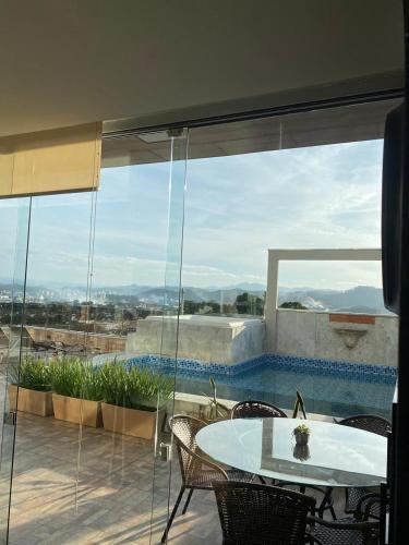 a room with a table and chairs and a large window at Doce Despertar Suítes in Brusque