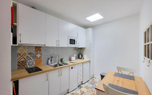 Una cocina con gabinetes blancos y una mesa de madera. en Casa Miradouro das Beatas, en Elvas