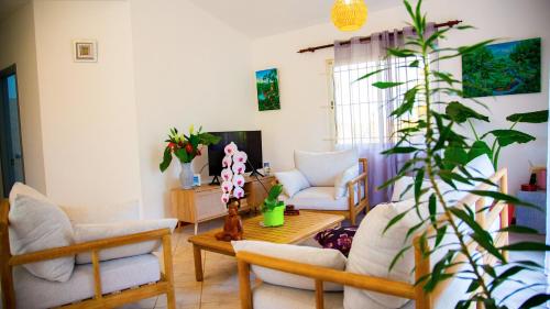 a living room with chairs and a table and a plant at VILLA CANELLE in Trou aux Biches