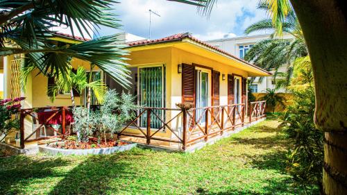 a yellow house with a porch and some palm trees at VILLA CANELLE in Trou aux Biches