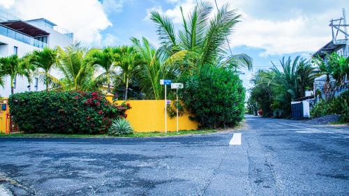 an empty street with palm trees and a yellow wall at VILLA CANELLE in Trou aux Biches