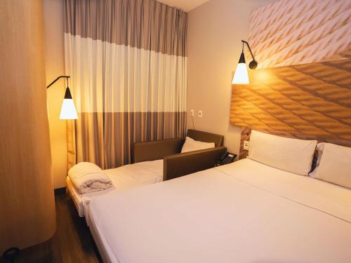 a hotel room with two beds and a chair at ibis Sao Bernardo do Campo in São Bernardo do Campo