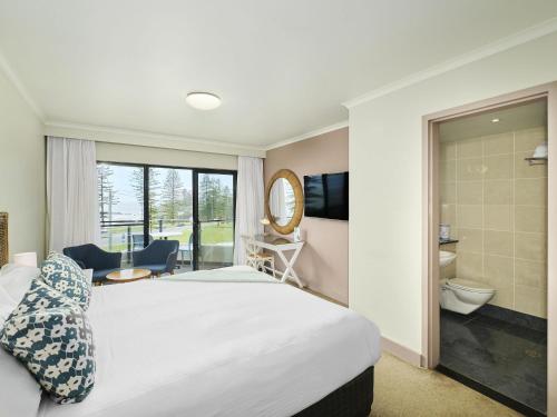 a hotel room with a bed and a bathroom at ibis Styles Port Macquarie in Port Macquarie
