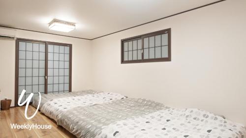 a white bedroom with a bed and two windows at WeeklyHouse BiwakoOtsu in Otsu