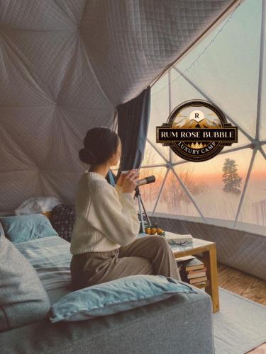 a woman sitting on a bed in a tent at RUM ROSE BUBBLE lUXURY CAMP in Wadi Rum