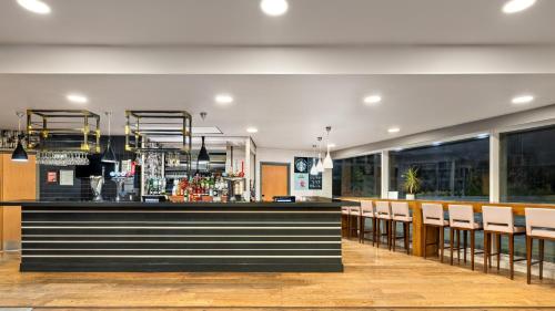a restaurant with a bar with white chairs at Holiday Inn Manchester-Mediacityuk by IHG in Manchester
