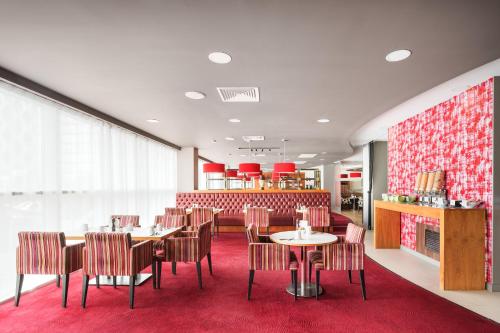 a restaurant with tables and chairs on a red rug at Holiday Inn Manchester-Mediacityuk by IHG in Manchester