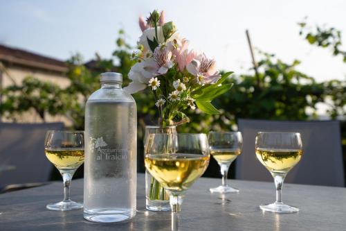 a bottle of white wine and three wine glasses on a table at Agriturismo Al Tralcio in Valeggio sul Mincio