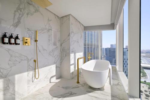 a bathroom with a white tub and marble walls at Kimpton KAFD Riyadh by IHG in Riyadh