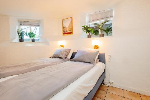 twee bedden in een kamer met twee ramen bij Just steps behind the Royal Palace in Oslo