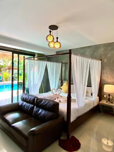 a bedroom with a canopy bed and a leather couch at Lanta Just Come Resort in Ko Lanta Yai
