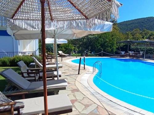 a pool with chairs and umbrellas next to a resort at Villa Riviera in Stavros