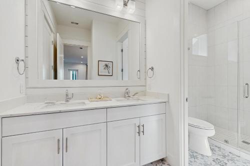 a white bathroom with two sinks and a toilet at Fairway to Heaven in Port Aransas