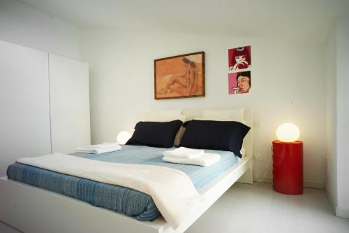 a white bedroom with a bed and a red lamp at Prione 132 in La Spezia