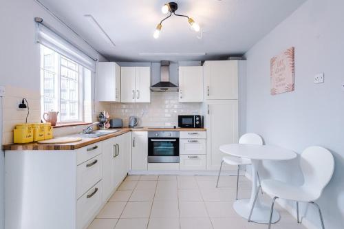 a kitchen with white cabinets and a table and chairs at Hough Green Cottage in Ashley