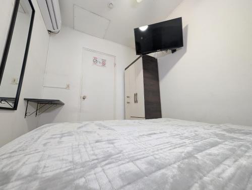 a bedroom with a bed with a flat screen tv on the wall at Hostal Yoha in Panama City