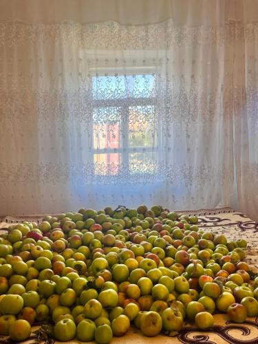 a pile of fruit on a bed with a window at ChudaK in Bokonbayevo