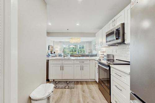 Biała kuchnia z białymi szafkami i oknem w obiekcie High Pointe 1115 w mieście Seacrest