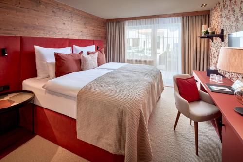 a hotel room with a large bed and a desk at Mount Med Resort in Oberau