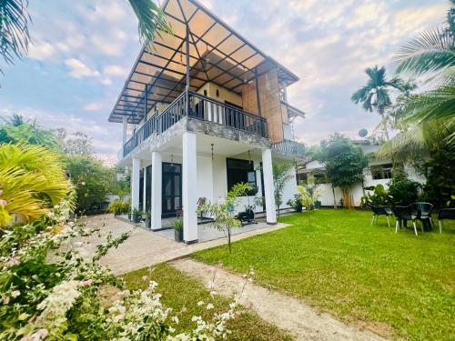 a house with a balcony and a yard at Meadow View Villa in Dickwella