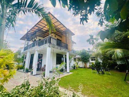 a house with a balcony and a yard at Meadow View Villa in Dickwella