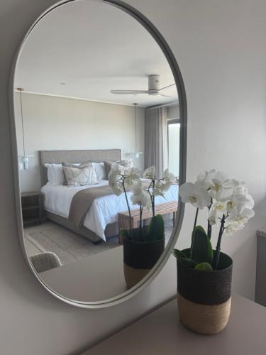 a mirror reflecting a bedroom with a bed and white flowers at Salt and Sand in Wilderness