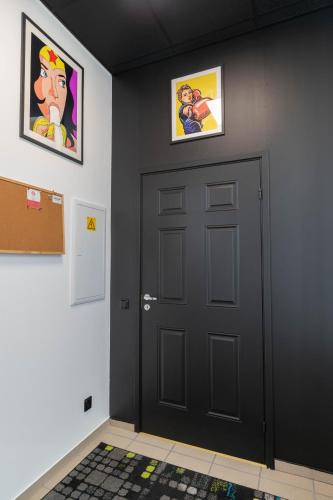 a black door in a room with two pictures on the wall at Apartments24 Black 1903 in Rakvere