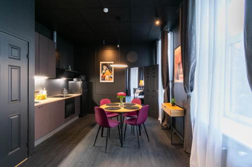 a small kitchen with a table and pink chairs at Apartments24 Black 1903 in Rakvere