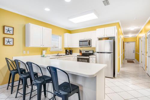 a kitchen with yellow walls and a counter with chairs at Marlin Key 3A in Orange Beach