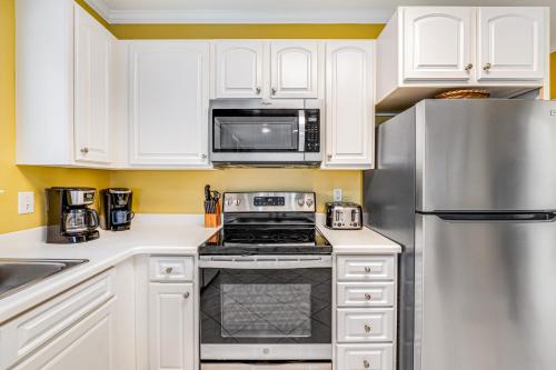 a kitchen with white cabinets and a stainless steel refrigerator at Marlin Key 3A in Orange Beach